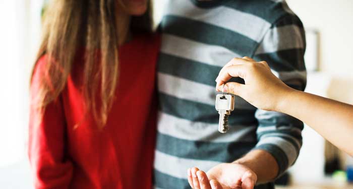 Young Couple Getting the Keys to Their New House That Will Need a Move In Cleaning.